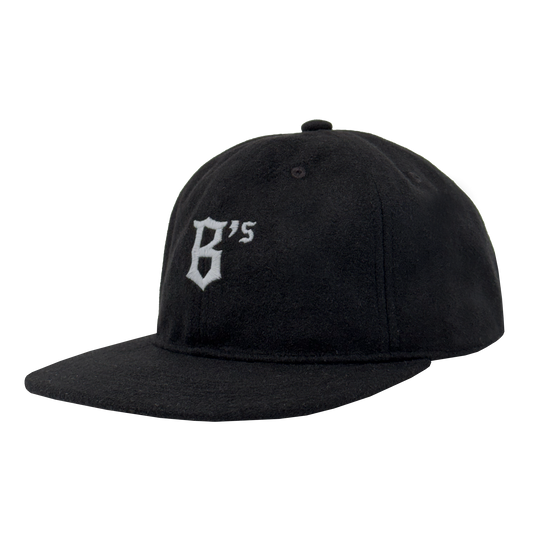 The Oakland Ballers B Strapback is a black flat-brim hat with "B's" in white old English font embroidered on the front, adjustable strapback, top button, and visible stitching. Brand: Oakland Ballers.