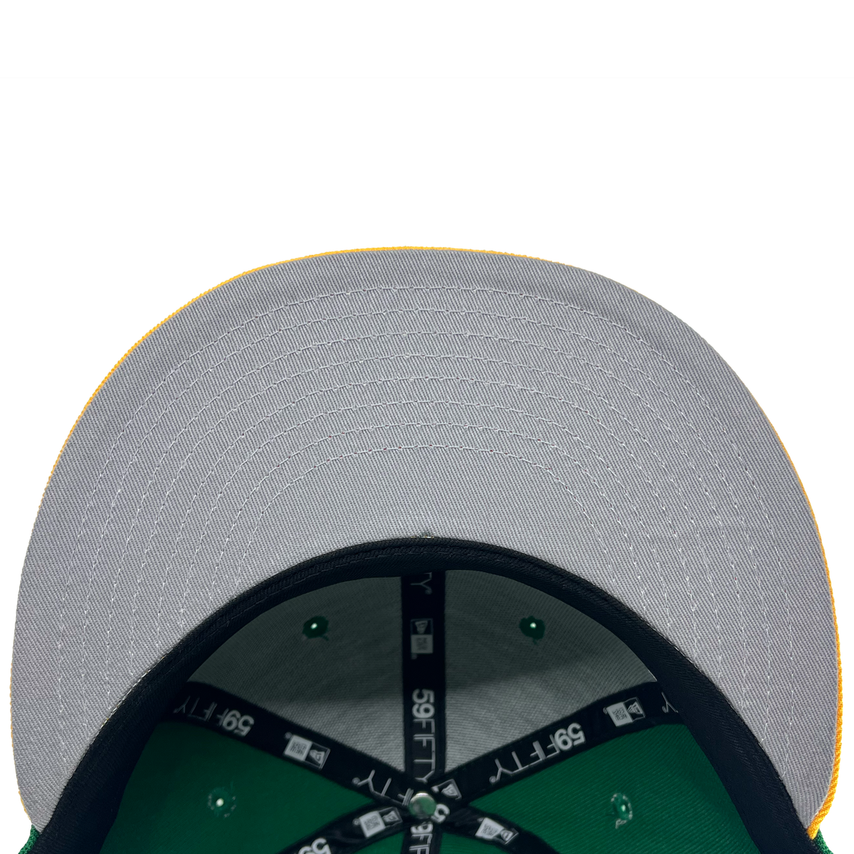 A close-up view of the underside of a New Era Oakland Ballers 59Fifty Cap's brim from their Pioneer League days. The brim is gray with visible stitching and a yellow edge. The interior showcases green fabric and black bands labeled "39THIRTY." Rivets on the green fabric are also evident, against a white background.
