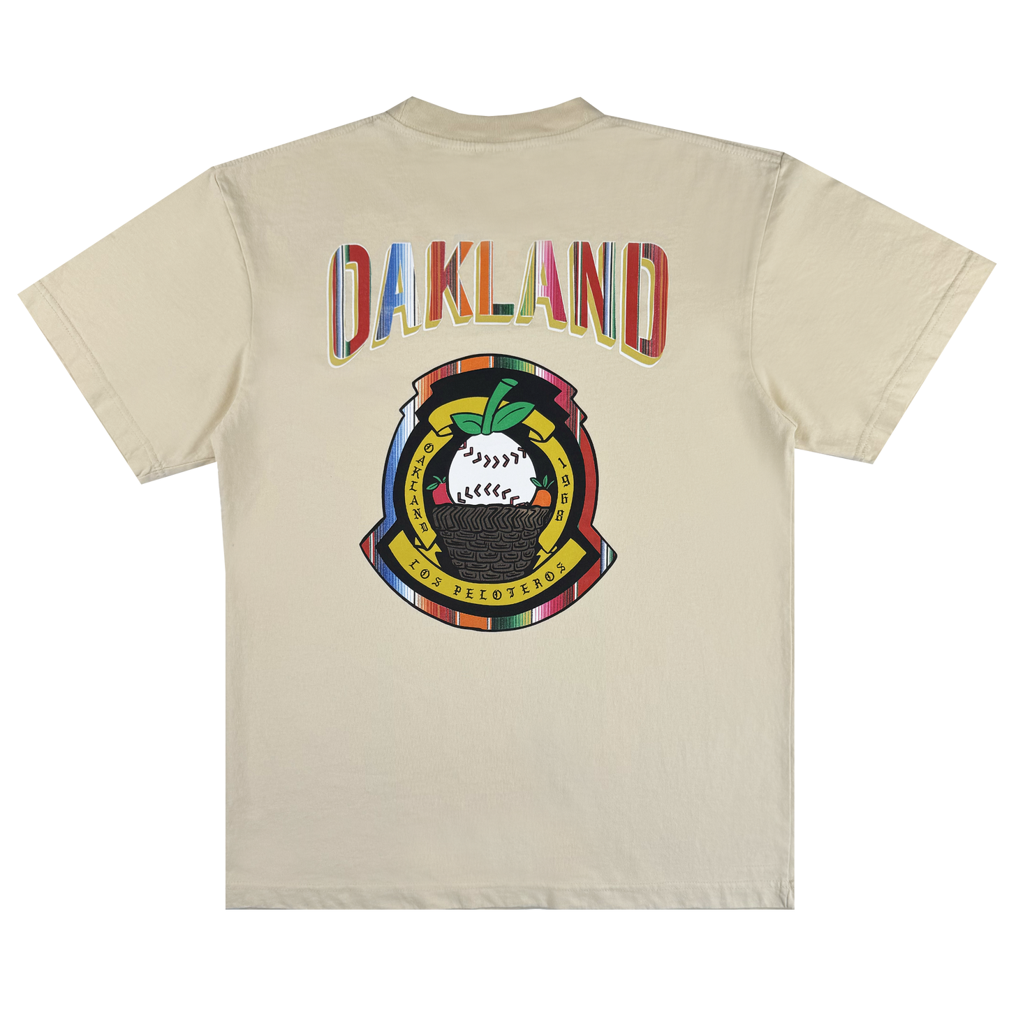 The Oakland Beisbol Tee by Oakland Ballers is a beige shirt featuring "OAKLAND" in bright letters on the back, plus a vibrant emblem with a baseball, green leaves, and "POR LOS PELOTEROS" on yellow and red banners.